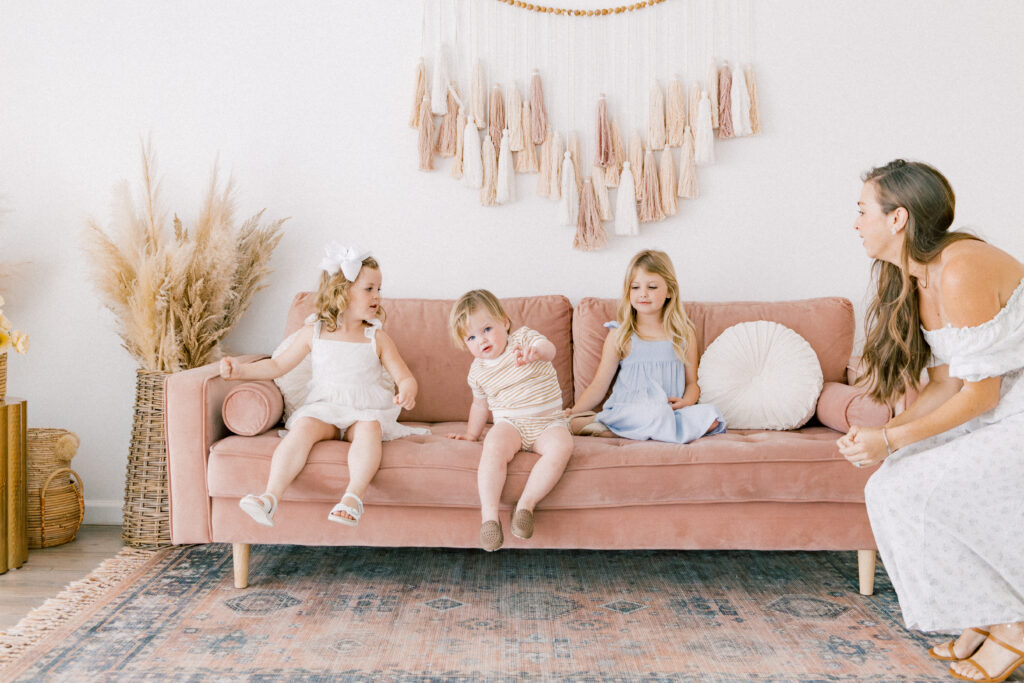 Mama watching her two daughters and her son sitting on a pink couch during a family portrait session by Fort Worth Family Photographer Cynthia Knapp